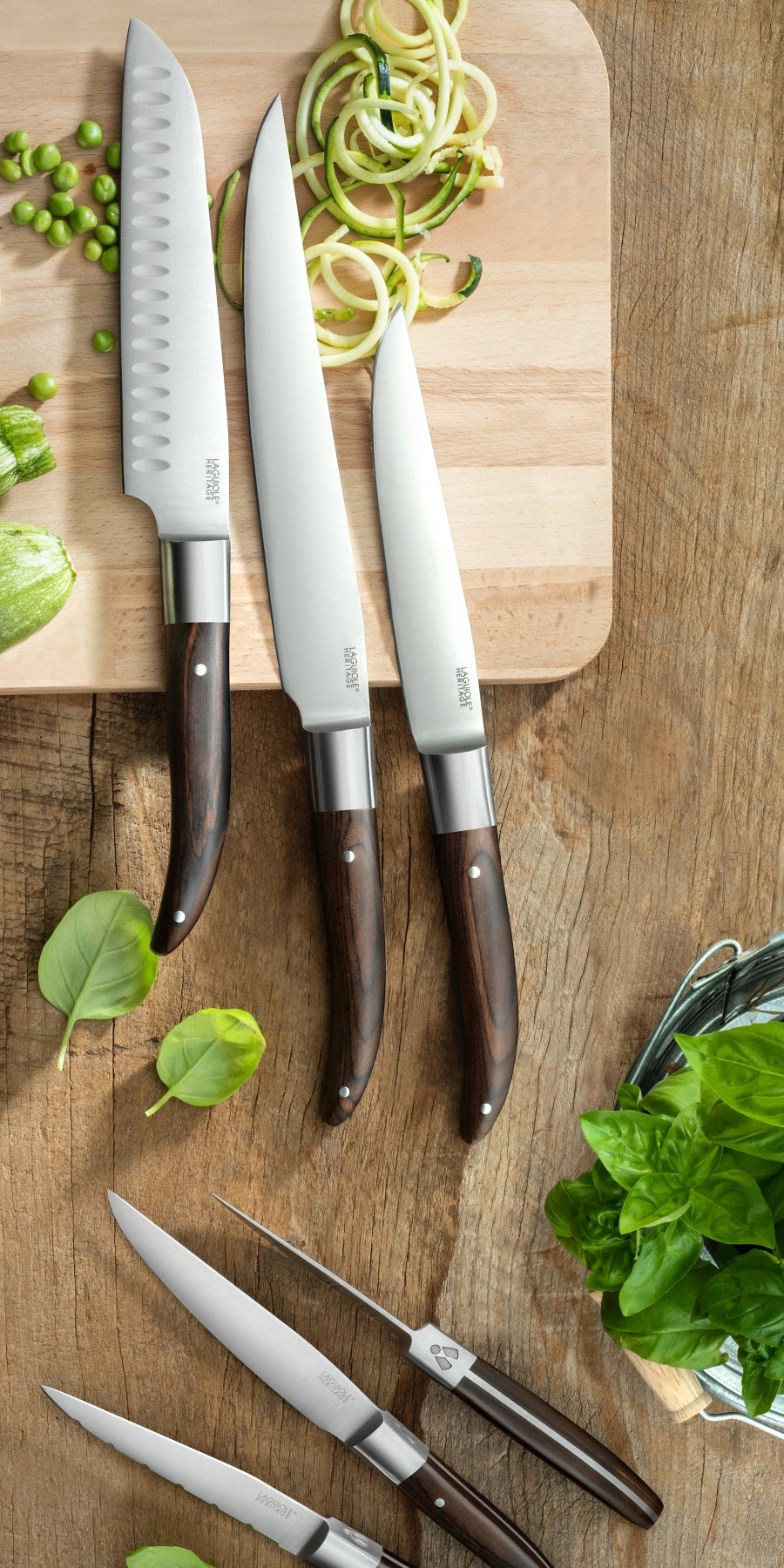 Several Laguiole heritage kitchen knives with wooden handles. The image background is made of light-colored wood.